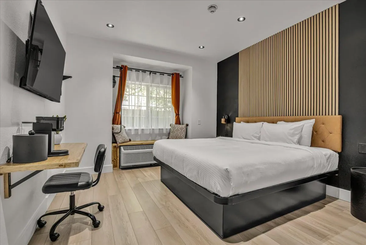 Boutique King – room view with wall-mounted desk, chair, TV, and curtained window
