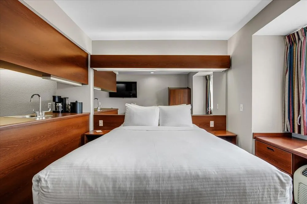 Classic Queen Suite – queen bed with cherry wood kitchenette, mirror, and microwave