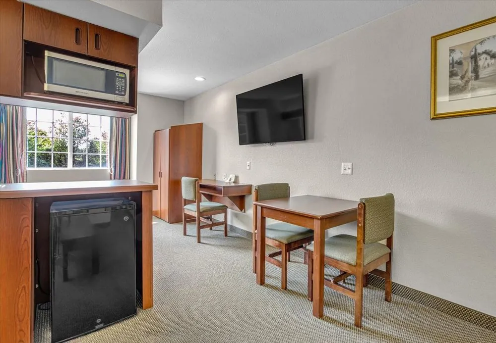 Classic Queen Suite – dining table and chairs with mini fridge and wall-mounted TV