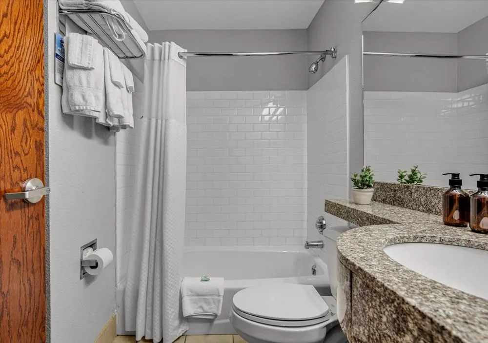 Classic Queen Suite – bathroom with granite-style vanity and tub-shower combo