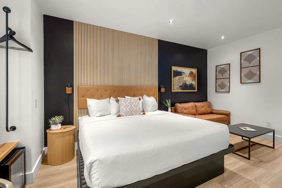 Boutique King Suite – king bed against black and wood slat accent wall with round nightstand