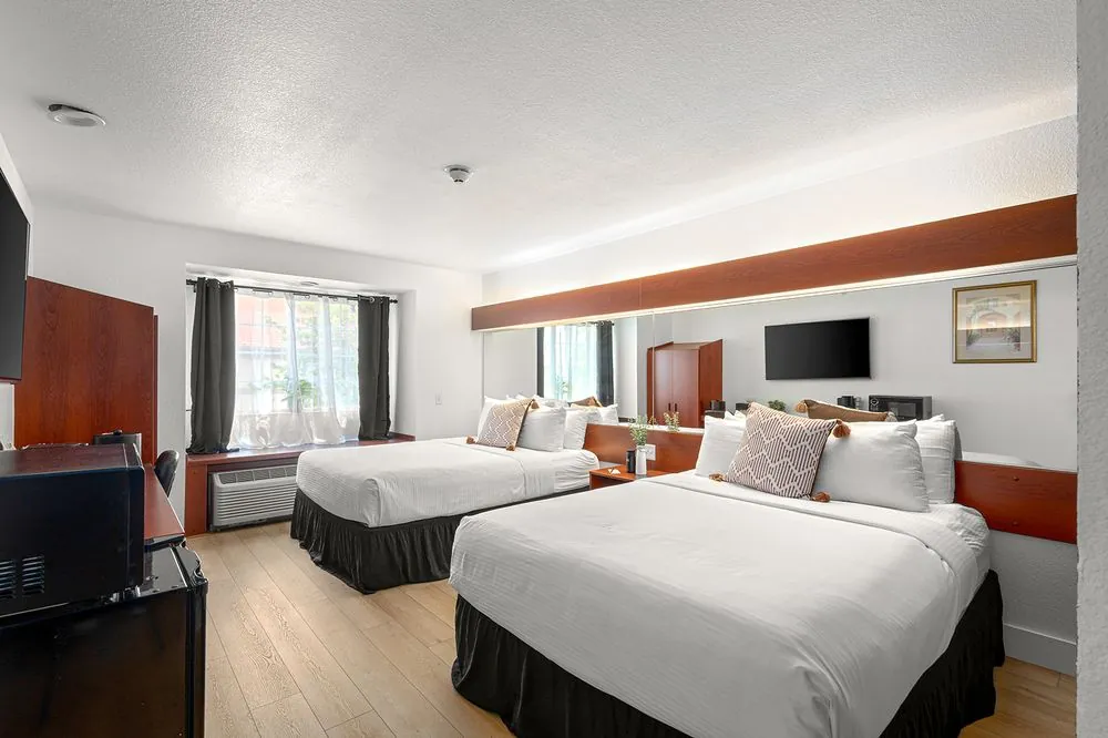 Classic Double Queen – double queen beds with cherry wood furniture and curtained window
