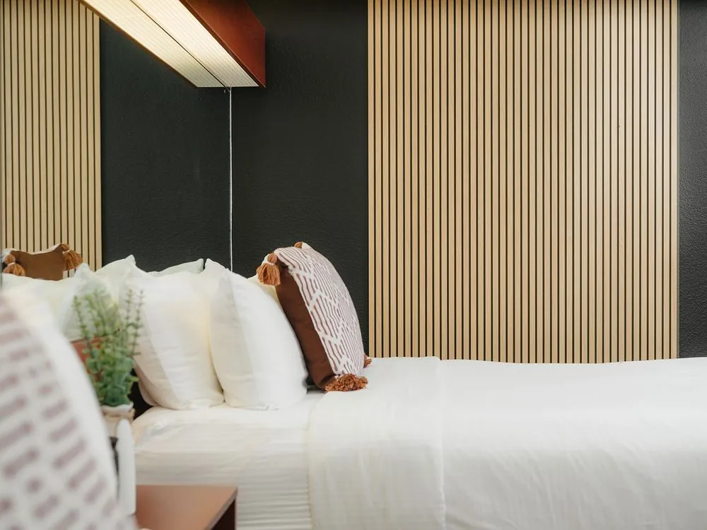 Classic Double Queen – bed against black and wood slat accent wall with blush pillow