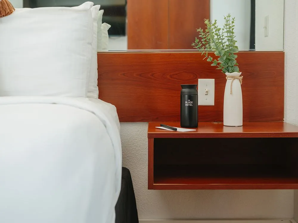 Classic Double Queen – bedside nightstand with lamp and fresh flowers