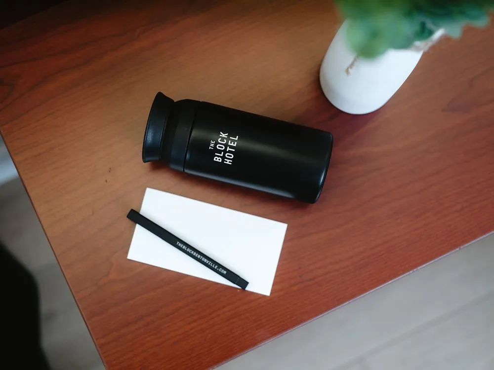 Classic Queen – work desk detail with notepad, pen, and travel tumbler