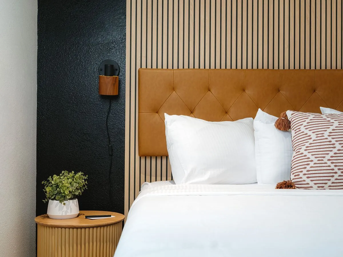 Boutique King Suite – close-up of cognac leather tufted headboard with patterned throw pillow